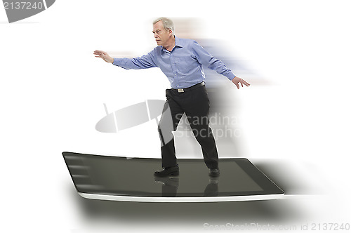 Image of Senior businessman keeping balance on a PC tablet
