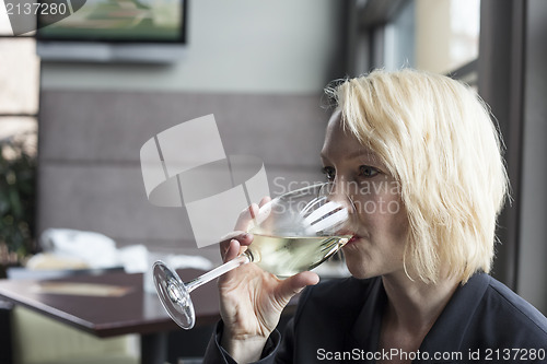 Image of Blonde Woman with Beautiful Blue Eyes Drinking Glass of White Wi