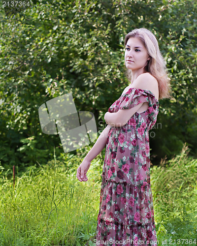 Image of Beautiful girl in floral dress stand in garden.