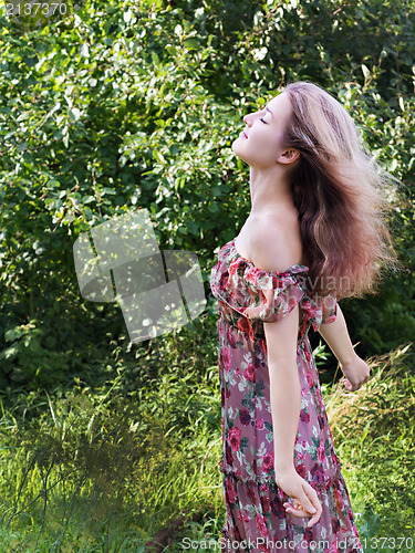 Image of Beautiful girl in floral dress stand in garden.