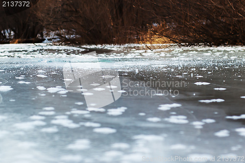 Image of Frozen river with blue ice and sun reflection. Selective focus.