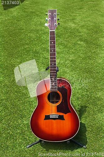 Image of Acoustic guitar on background of green grass.