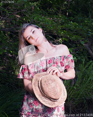 Image of Beautiful girl in the national dress and hat stand in the forest