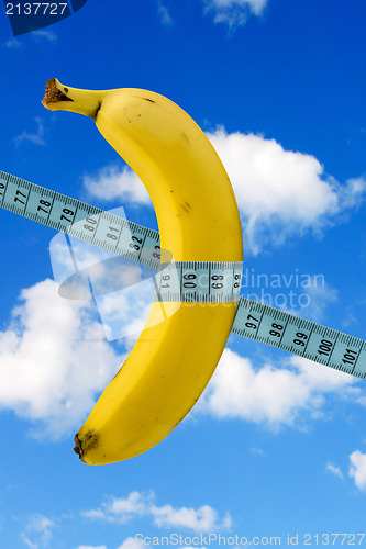 Image of banana with measure tape on sky background