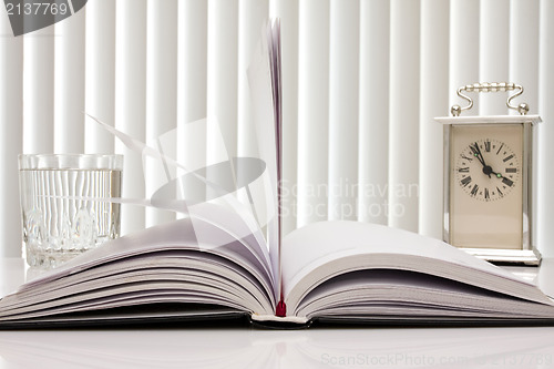 Image of book,clock and glass of water