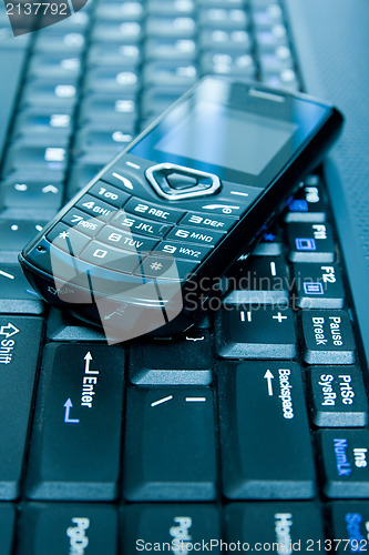 Image of mobile phone over laptop keyboard