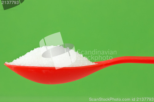 Image of spoon with sugar on green background