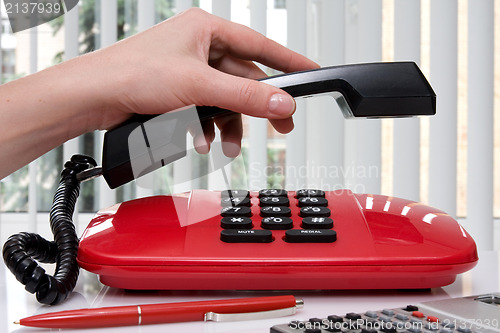 Image of  hand picking up the handset of telephone