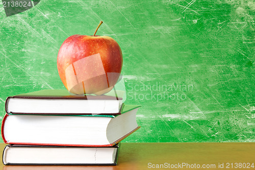 Image of books with apple against dirty chalkboard