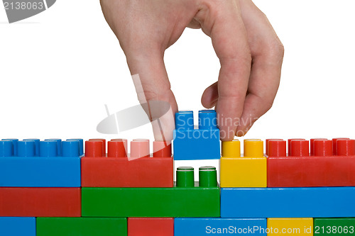 Image of hand building up lego wall