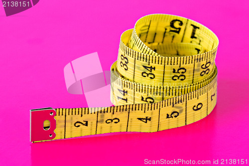 Image of measuring tape on vivid pink background