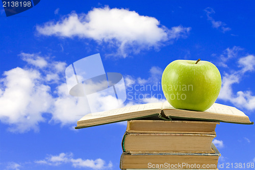 Image of books with apple on sky background