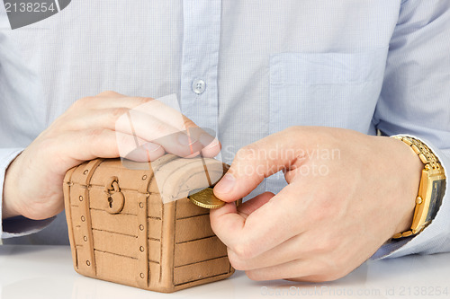 Image of hand putting coin into a money-box