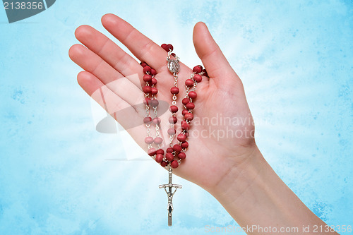 Image of hand with rosary on blue abstract background