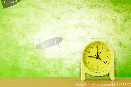 Image of green clock against dirty wall background