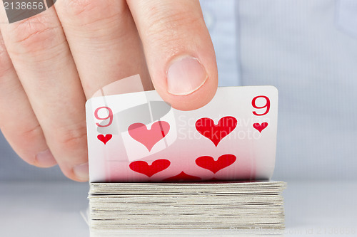 Image of hand revealing nine of hearts