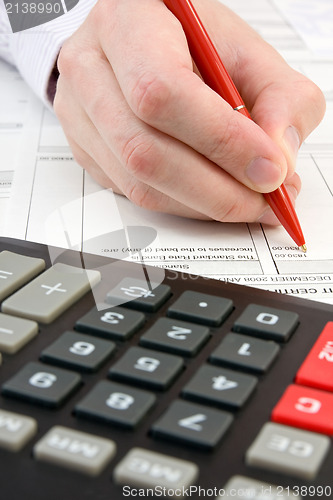 Image of calculator,documents and  hand with pen