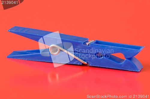 Image of blue plastic clothespin on red background