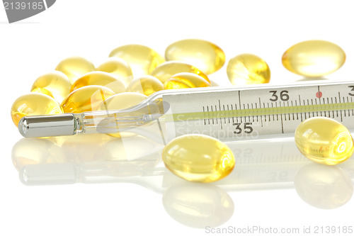 Image of medical thermometer and yellow pills 