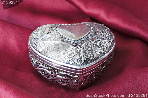 Image of silver  heart on red material background