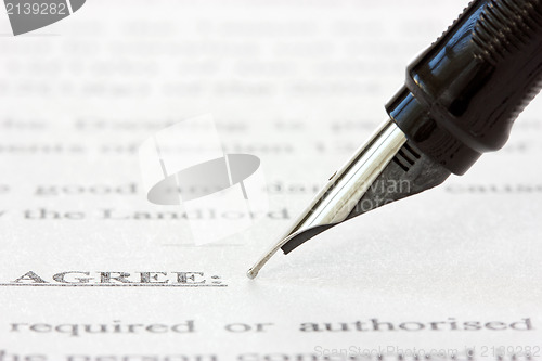 Image of ink pen over a printed agreement