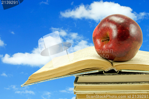 Image of books with apple on sky background