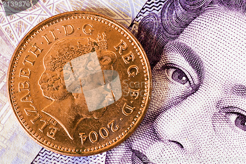 Image of one penny  on a twenty pounds banknote