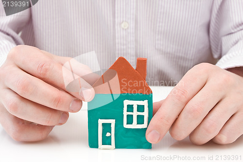 Image of hands making house from plasticine