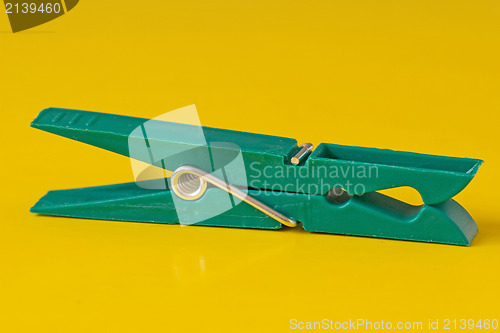 Image of green plastic clothespin on yellow background