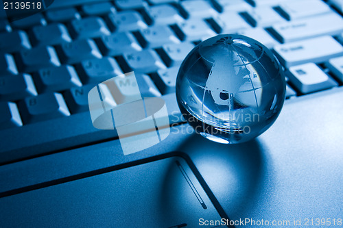 Image of transparent globe on a laptop  keyboard 