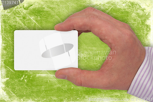 Image of hand with white card on green background