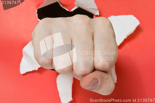 Image of Hand punching through red paper 