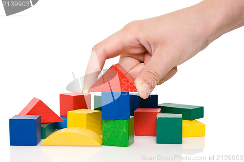 Image of hand make a building of colored blocks