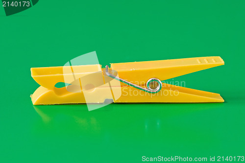 Image of yellow plastic clothespin  on green background