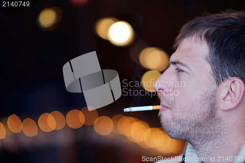 Image of man smokes a cigaret against a dark background