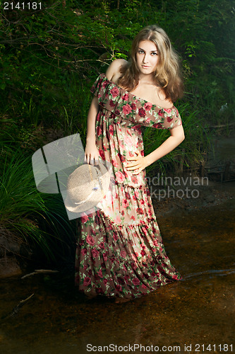 Image of Beautiful girl in the national dress and hat stand in the river 