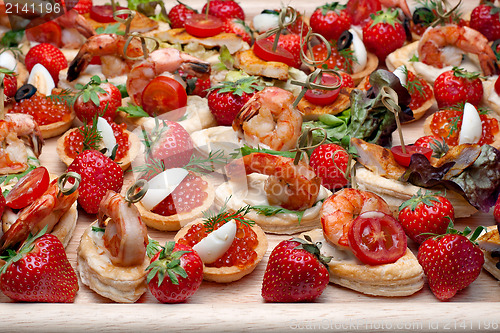 Image of Lot of canape with  shrimp, caviar, strawberries and other on wo