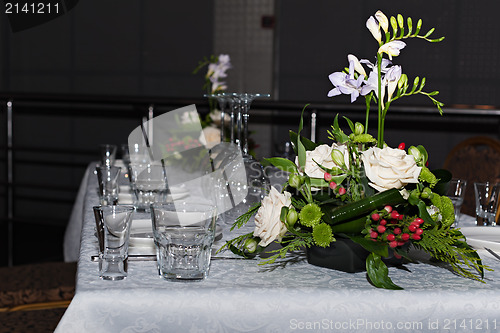 Image of Flower composition of freesia, roses and hypericum on tables set