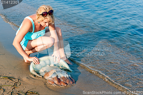 Image of young woman try to help the big blue jellyfish throw the Japanes