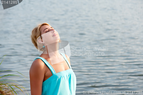 Image of portrait of a young woman closed her eyes from the evening sun o