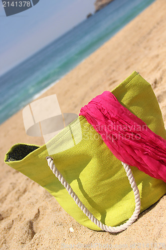 Image of Green beach bag on the seacoast and pink shawl  