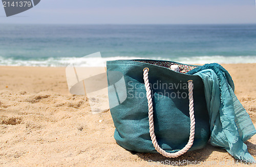 Image of Blue beach bag on the seacoast and shawl  