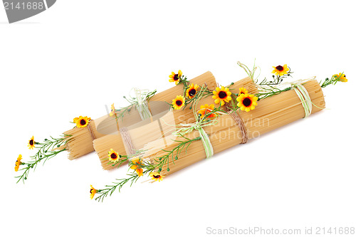 Image of Uncooked Italian spaghetti decorated with yellow flowers isolate