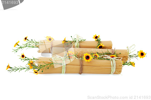 Image of Uncooked Italian spaghetti decorated with yellow flowers isolate