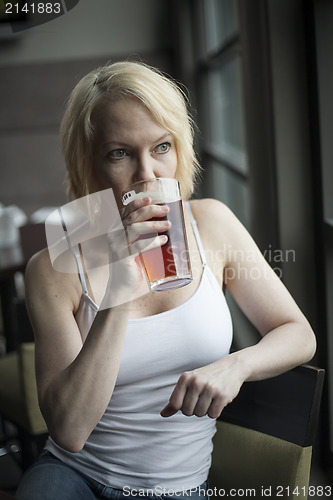 Image of Blonde Woman with Beautiful Blue Eyes Drinking Glass of Pale Ale