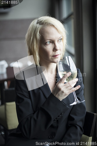 Image of Blonde Woman with Beautiful Blue Eyes Drinking Glass of White Wi