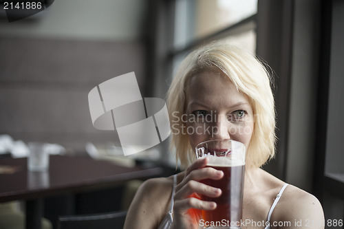 Image of Blonde Woman with Beautiful Blue Eyes Drinking Glass of Pale Ale