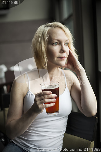 Image of Blonde Woman with Beautiful Blue Eyes Drinking Glass of Pale Ale