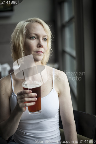 Image of Blonde Woman with Beautiful Blue Eyes Drinking Glass of Pale Ale