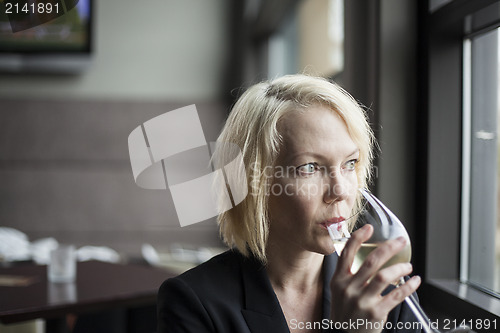 Image of Blonde Woman with Beautiful Blue Eyes Drinking Glass of White Wi